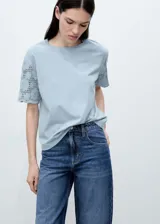 Camiseta blanca de algodón con mangas cortas de crochet y cuello redondo. Diseño recto y calce holgado.