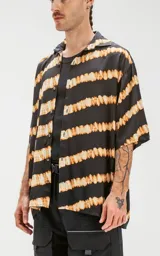 Camisa de manga corta con estampado de rayas horizontales difuminadas en tonos beige y negro, de calce oversize y canesú en la espalda.