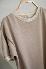 Remera color beige de tejido artesanal en hilado 70% algodón y 30% acrílico, con cuello redondo y mangas cortas.