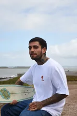 Remera negra de algodón con cuello redondo y mangas cortas. Estampado pequeño en el pecho con un diseño abstracto en tonos naranja y amarillo.