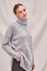 Sweater beige con cuello alto doble, textura acanalada y tajos laterales.