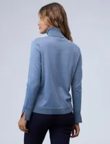 Polera de punto fino marca Nienty, color blanco, con cuello alto volcado y mangas largas con detalle de tajo en los puños.