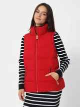 Chaleco rojo acolchado con cuello alto, cierre frontal con cremallera dorada y bolsillos laterales con cremallera dorada.