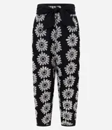 Pantalón zanahoria de cintura alta, confeccionado en laise negro con bordado floral blanco y lazo en la cintura.