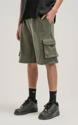 Bermuda de algodón rústico color verde militar, calce oversize, con elástico en la cintura y bolsillos cargo con cierre.