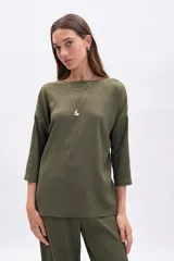 Remera de manga tres cuartos, color verde oliva, con cuello bote y textura arrugada. Corte holgado.