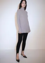 Conjunto de jersey y pantalón de punto acanalado color gris topo. El jersey es de cuello alto con cremallera, manga larga acampanada y corte entallado.