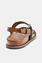 Sandalias planas color marrón con doble tira delantera con detalle de hebilla. Cierre mediante hebilla en la pulsera al tobillo.