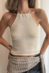 Top halter tejido en color beige, con tiras finas que se atan al cuello y espalda descubierta.