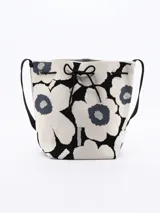 Bolso bandolera tipo bucket con estampado de flores en blanco y negro, con ajuste superior de cordón y correa larga de hombro negra.