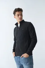 Campera marrón de algodón con cierre frontal, cuello alto, bolsillos laterales, puños y logo bordado en el pecho.