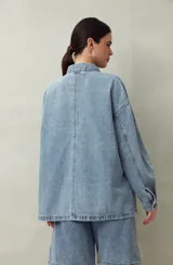 Sobrecamisa oversize de jean azul con cuello camisero, cierre frontal con botones, mangas largas y bolsillos de parche en el pecho.
