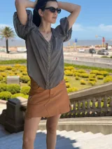 Camisa de gasa color gris oscuro, con mangas globo y una tira central vertical decorada con piedras azules.