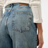 Pantalón de jean celeste, de corte recto y tiro alto, con lavado gastado y dobladillo ancho.