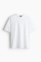 Remera blanca de algodón de peso medio, con cuello redondo ribeteado, hombros caídos y bajo recto. Corte oversized.