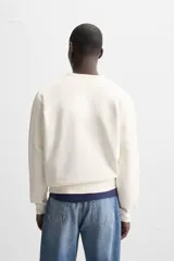Sudadera negra de corte holgado, cuello redondo y mangas largas con puños acanalados.