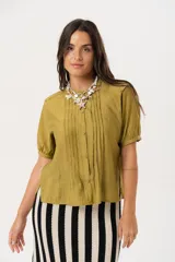 Blusa color verde oliva con cuello mao, mangas cortas abullonadas y cierre frontal con botones.