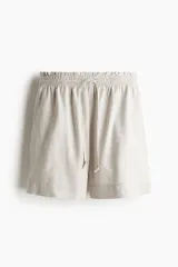 Short color beige de tiro alto con cintura elástica fruncida con ribete de volado, cordón para ajustar fino con cuentas de metal y bolsillos laterales discretos.