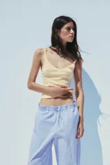 Pantalón tipo barrel con rayas verticales celestes y blancas, tiro medio y cintura elástica ajustable con lazo. Tiene bolsillos laterales y falsos bolsillos de vivo en la espalda.