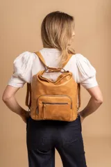 Cartera mochila color tostado, símil cuero, con compartimiento principal amplio y bolsillos frontales con cierre. Tiene correas ajustables para usar como mochila y asa superior para llevar al hombro.