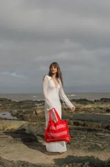 Bolso tipo tote tejido a crochet, con hilo 100% algodón, a rayas horizontales color crema y lila, con volados en los bordes y manijas reforzadas.