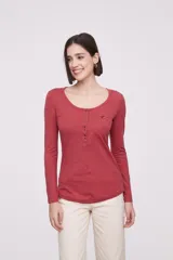 Remera de manga larga entallada en color blanco, confeccionada en algodón. Presenta cuello redondo con una hilera de botones frontales y un pequeño bolsillo en el pecho con detalle de botón.