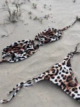 Conjunto de bikini con estampado animal print, compuesto por un corpiño triangular con tiras finas y una bombacha cavada con tiras laterales ajustables.