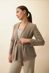 Chaqueta corta color beige, entallada, con escote en V, manga larga y cierre frontal con lazo fijo. Confeccionada en lana fina sin teñir, con bolsillos escondidos y terminaciones enviadas. Hecha 100% en Uruguay.