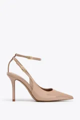 Zapato de tacón destalonado color nude, con efecto charol, punta fina y pulsera al tobillo con hebilla metálica.