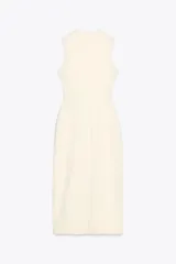 Vestido midi color crema, de cuello redondo y sin mangas. Presenta falsos botones frontales, cinturón elástico con aplique dorado, bolsillos de parche con solapa y abertura delantera.