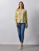Blusa de gasa verde con estampado de flores blancas y celestes. Tiene cuello a la base con escote en V y mangas 3/4 fruncidas.
