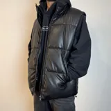 Chaleco puffer negro simil cuero con cierre frontal y bolsillos laterales.