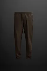 Pantalón deportivo color marrón oscuro, corte regular fit, confeccionado en tejido técnico ligero y elástico. Cuenta con cintura elástica ajustable con cordón, bolsillos frontales con cierre de cremallera, bolsillo trasero con cierre de cremallera oculta en costura y bajo ajustable con elástico.