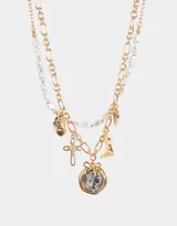 Collar corto dorado de doble cadena, una de eslabones y otra de perlas sintéticas. Incluye dijes de cruz, bota cowboy, moneda antigua y otros.