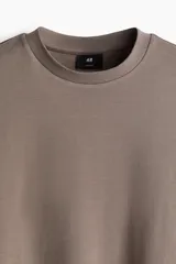 Remera color marrón topo de punto de algodón pesado, con cuello redondo ribeteado, hombros caídos y bajo recto. Corte holgado.
