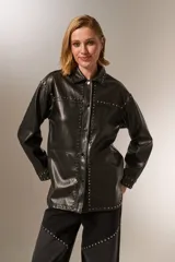 Chaqueta negra de eco-cuero con cuello camisero, corte holgado, cierre con broches y tachas plateadas.