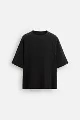 Camiseta negra de corte relaxed fit, cuello redondo y mangas cortas. Tejido de punto con textura acanalada y efecto lavado.