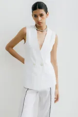 Chaleco sastrero color crema de lino, con cuello en V profundo y cierre cruzado con botón.