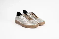 Zapatillas deportivas plateadas con cordones color beige y suela marrón.