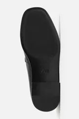 Mocasín de cuero negro con suela a tono y ligero tacón.