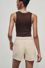 Falda pantalón corta color crudo, de tiro alto con delantero cruzado y cierre con cremallera oculta y botones.