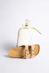 Sandalias de cuero color beige con dos tiras anchas y hebillas doradas ajustables.