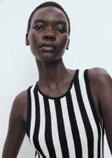 Vestido largo de punto fino, con tirantes anchos y cuello caja. Presenta un estampado de rayas verticales en blanco y negro, y un bajo asimétrico.