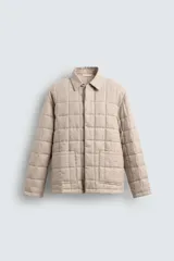 Cazadora color beige de lino y algodón acolchado, corte relaxed fit, cuello solapa, manga larga, bolsillos frontales de parche y cierre frontal con botones ocultos.