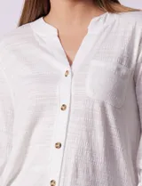 Blusa blanca texturizada marca Ninety, con cuello a la base, escote en V, abertura central con botones, bolsillo delantero y mangas tres cuartos regulables con presilla y botón.