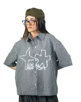 Camisa unisex a cuadros blancos y negros con estampado de texto en el frente, corte holgado y mangas cortas.
