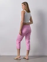 Pantalón capri color rosa de tencel elastizado con bolsillos simulados en la parte delantera y bolsillos aplicados en la parte trasera. Tiene pretina ancha, corte recto y terminación de ruedo desflecado.