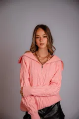 Buzo de punto color rosado, con cuello polo y cierre frontal parcial, de manga larga y diseño holgado.