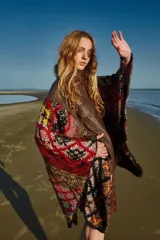 Poncho de cuero ovino con corte de chaqueta y mangas tejidas en lana con diseño geométrico multicolor. Talle único.