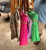Bolso de lona color verde con manijas marrones y etiqueta con logo.